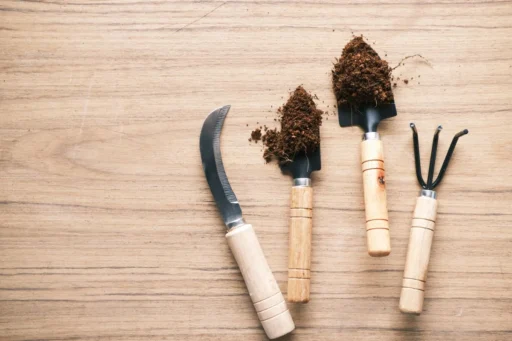 Gardening hand tools and soil arranged on a wooden table